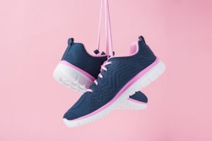 Αθλητικά παπούτσια στον αέρα με ροζ φόντο